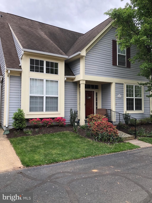 view of front of property with a shingled roof and a front lawn