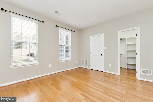 unfurnished bedroom with light wood-type flooring, visible vents, and baseboards