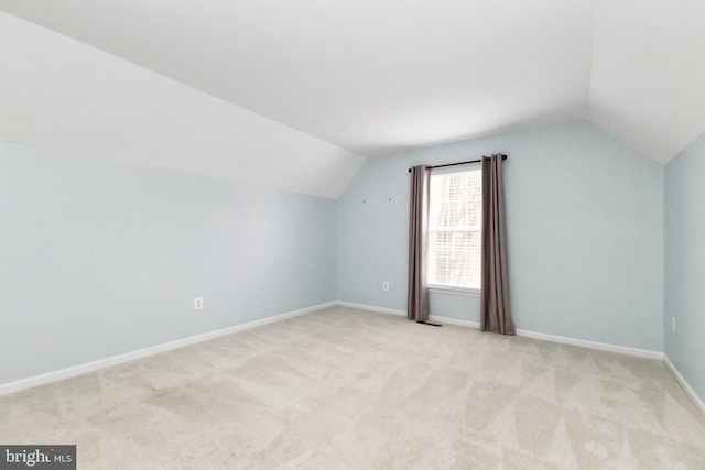 additional living space featuring lofted ceiling, light carpet, and baseboards