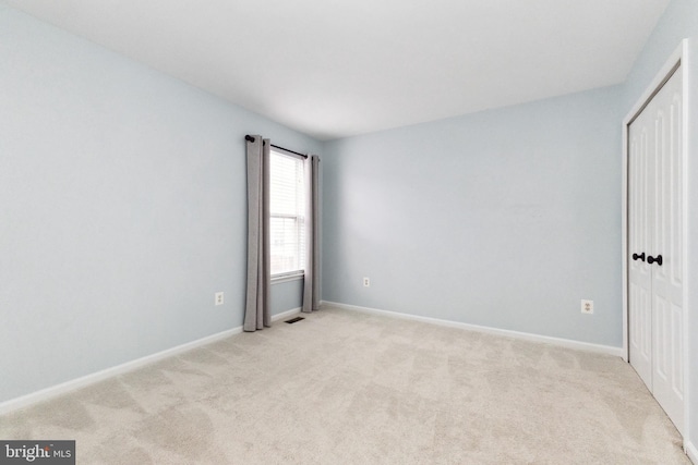 empty room featuring light carpet and baseboards