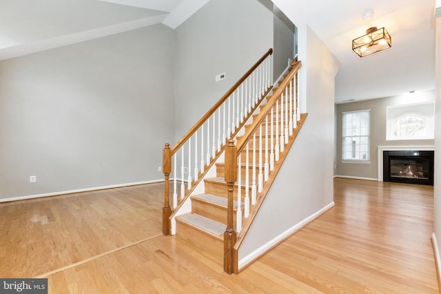 stairs with a glass covered fireplace, baseboards, and wood finished floors