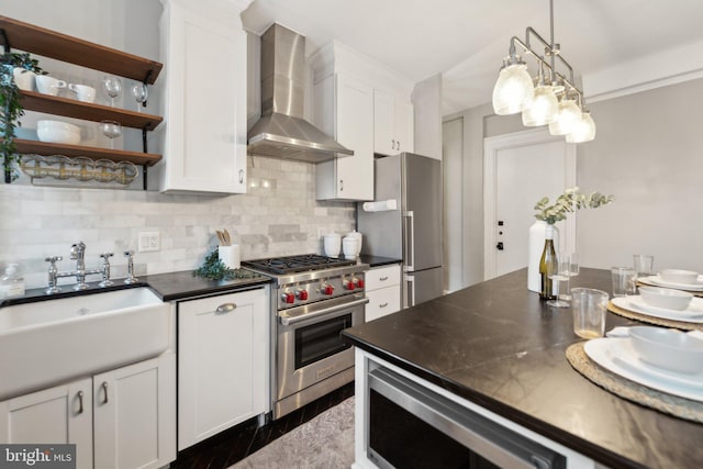 kitchen with stainless steel appliances, tasteful backsplash, white cabinetry, a sink, and wall chimney range hood