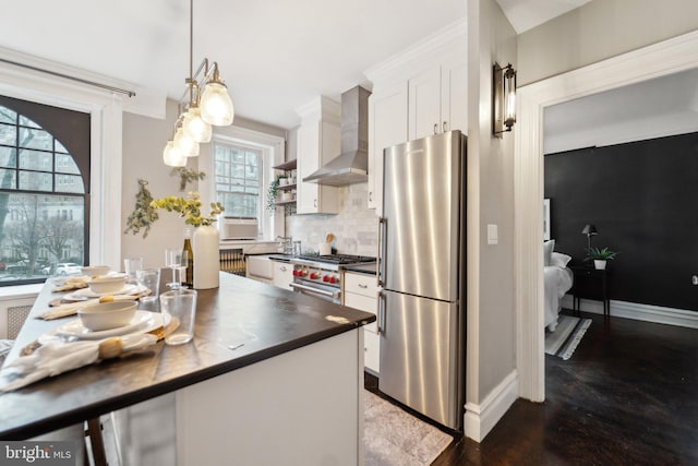 kitchen featuring stainless steel appliances, tasteful backsplash, wall chimney exhaust hood, and white cabinetry