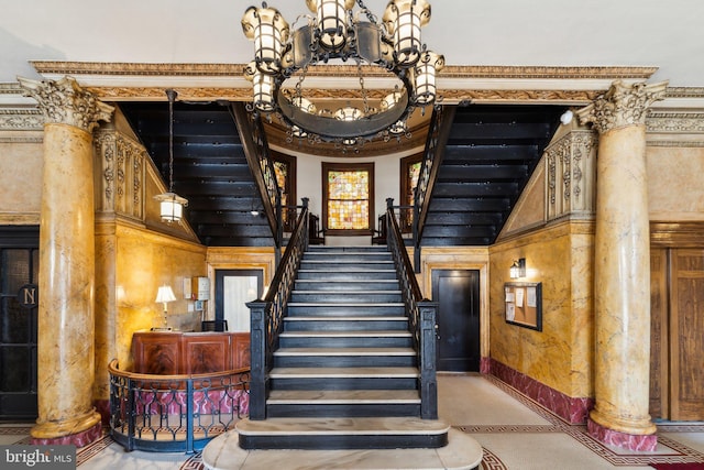 stairs featuring baseboards, decorative columns, and a notable chandelier