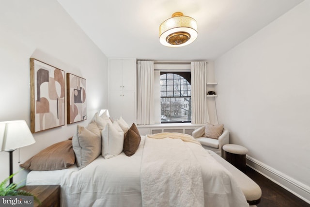 bedroom with baseboards and dark wood-type flooring