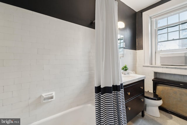 bathroom with toilet, a wainscoted wall, tile walls, radiator heating unit, and shower / bath combo