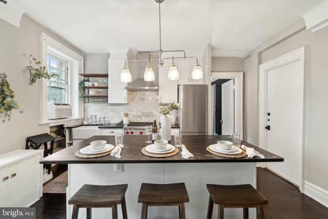 kitchen with freestanding refrigerator, white cabinetry, dark countertops, and decorative backsplash