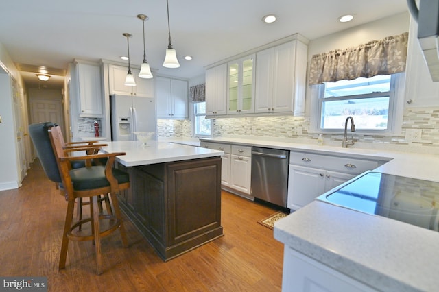 kitchen with white refrigerator with ice dispenser, white cabinetry, light countertops, and stainless steel dishwasher