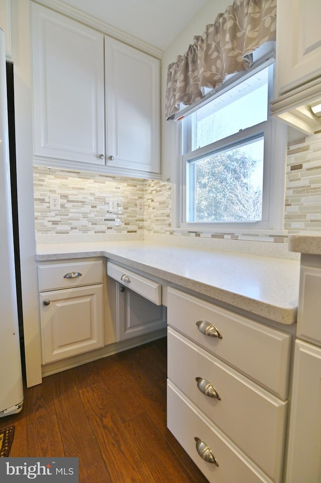 kitchen with decorative backsplash, dark wood-style floors, freestanding refrigerator, light stone countertops, and white cabinetry