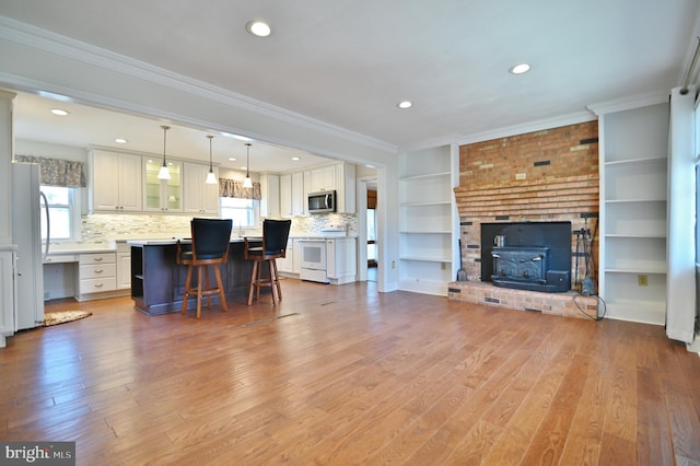 living room with a healthy amount of sunlight, light wood-style flooring, and ornamental molding