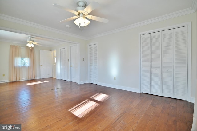 interior space featuring crown molding, wood-type flooring, and multiple closets