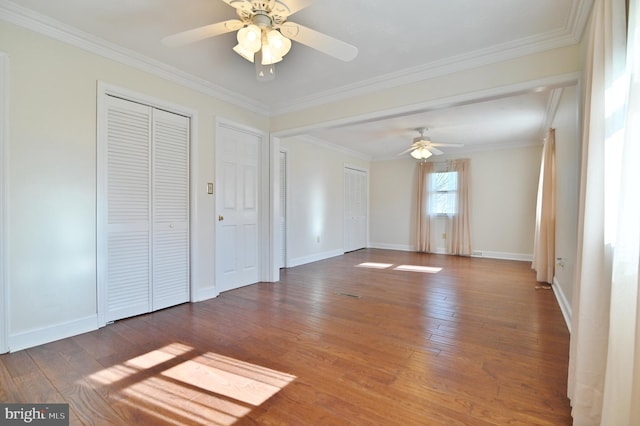 unfurnished bedroom featuring two closets, baseboards, and hardwood / wood-style flooring