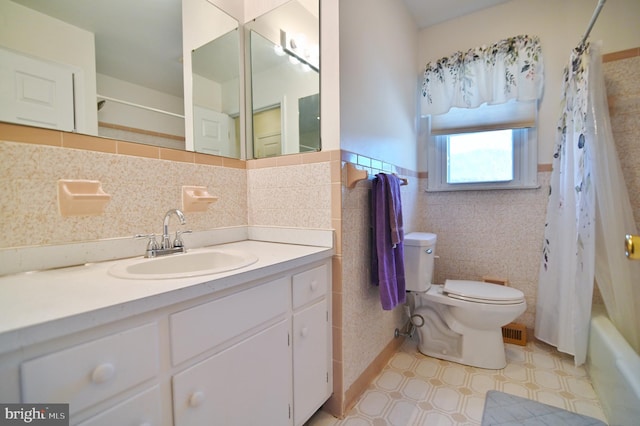 bathroom featuring tile walls, toilet, shower / bath combo, wainscoting, and vanity