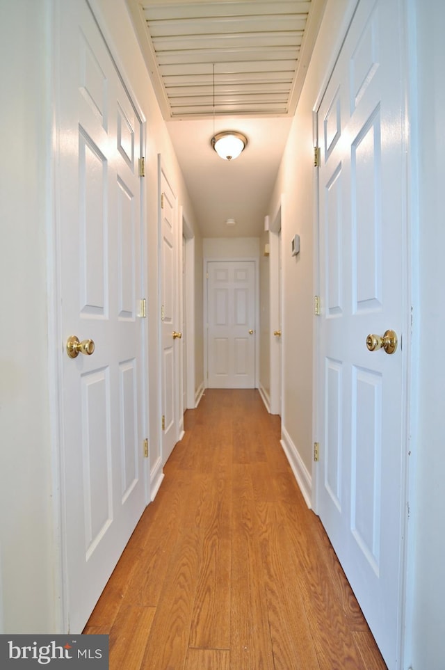 hall with baseboards and light wood-style floors