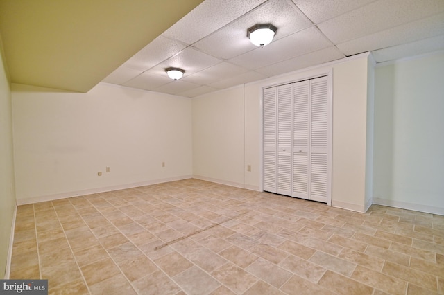 finished basement with a paneled ceiling and baseboards