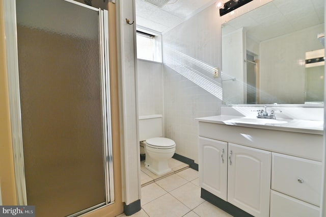 bathroom featuring a stall shower, toilet, tile patterned floors, vanity, and tile walls