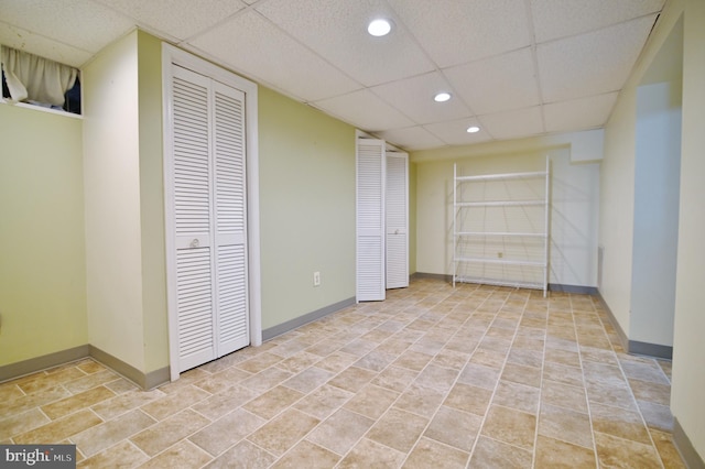 finished below grade area featuring baseboards, a drop ceiling, and recessed lighting