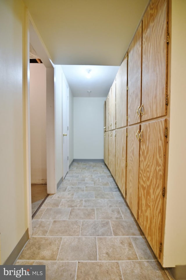 corridor featuring stone finish floor and baseboards