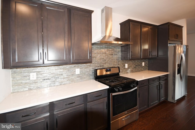 kitchen with dark wood-style floors, stainless steel appliances, tasteful backsplash, dark brown cabinetry, and wall chimney exhaust hood