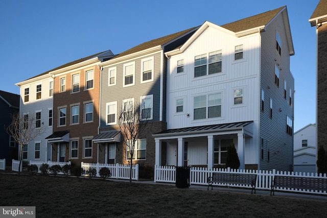 view of front of property with metal roof, a standing seam roof, board and batten siding, and a fenced front yard