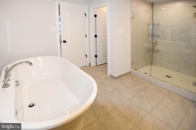 bathroom with a stall shower, baseboards, a freestanding tub, and tile patterned floors