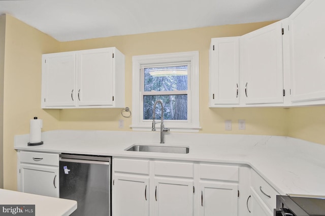 kitchen featuring light countertops, stainless steel dishwasher, a sink, and white cabinetry