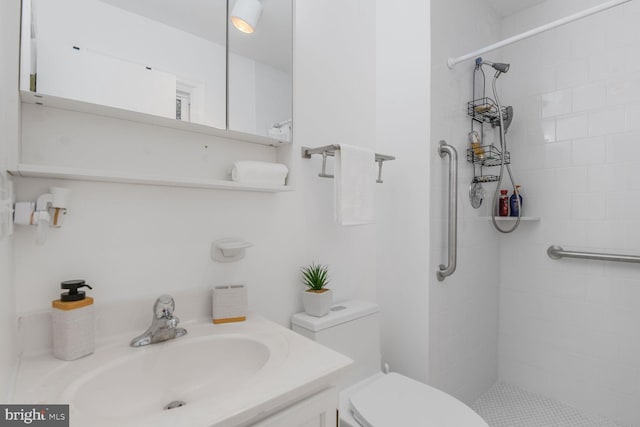 full bath featuring vanity, a tile shower, and toilet