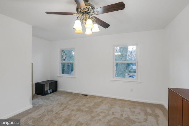 unfurnished room featuring a ceiling fan, light colored carpet, visible vents, and baseboards