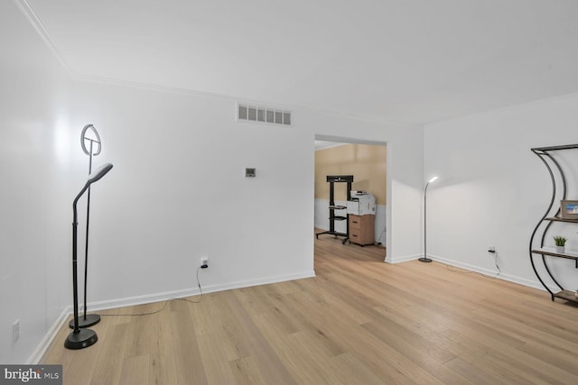 interior space featuring baseboards, visible vents, wood finished floors, and ornamental molding