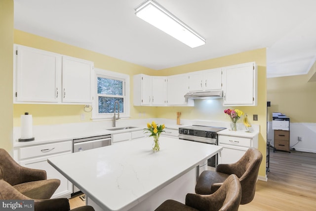 kitchen featuring stainless steel appliances, a kitchen bar, a sink, and white cabinets