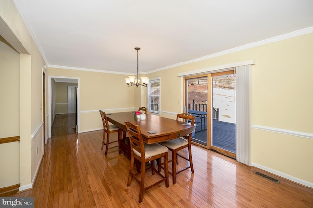 dining room featuring crown molding, visible vents, an inviting chandelier, baseboards, and hardwood / wood-style flooring