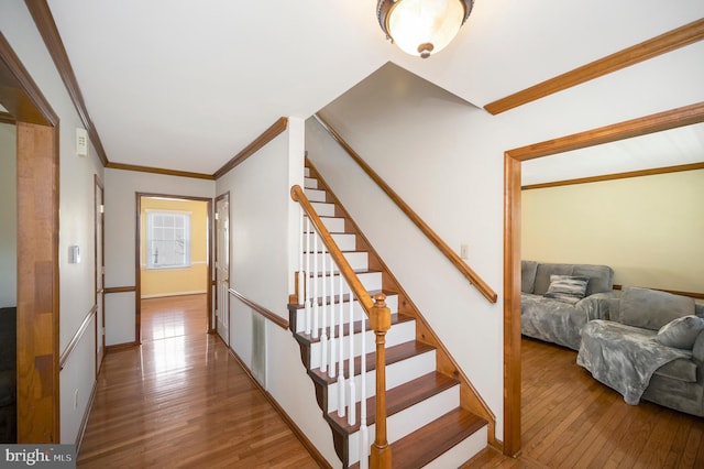 staircase featuring ornamental molding, baseboards, and hardwood / wood-style flooring