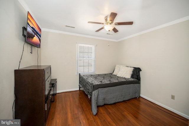 bedroom featuring visible vents, ornamental molding, a ceiling fan, wood finished floors, and baseboards