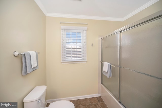 bathroom with baseboards, toilet, shower / bath combination with glass door, tile patterned floors, and crown molding