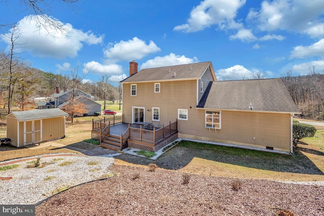 rear view of property featuring an outbuilding, a deck, roof with shingles, a shed, and a chimney