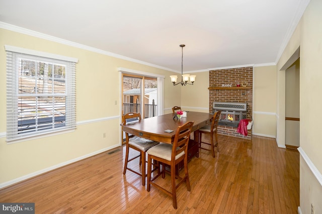 dining room with plenty of natural light, ornamental molding, wood-type flooring, and a chandelier