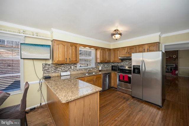 kitchen featuring brown cabinetry, dark wood finished floors, a peninsula, stainless steel appliances, and under cabinet range hood