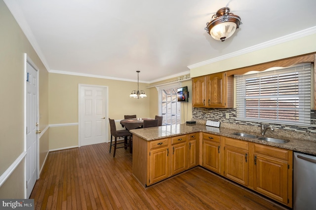 kitchen featuring dark wood-style flooring, stainless steel dishwasher, ornamental molding, a sink, and a peninsula