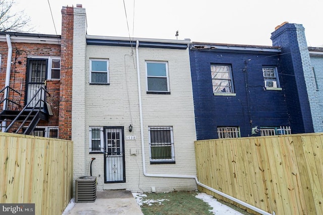 back of property with central air condition unit, fence, and brick siding