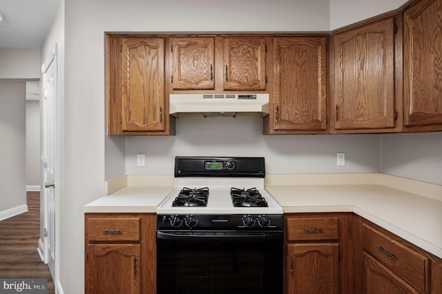 kitchen with light countertops, gas stove, brown cabinets, and under cabinet range hood