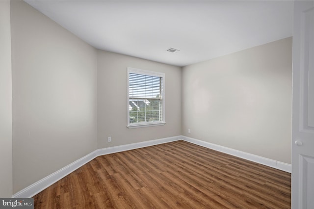 unfurnished room featuring wood finished floors, visible vents, and baseboards