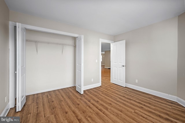 unfurnished bedroom featuring a closet, baseboards, and wood finished floors