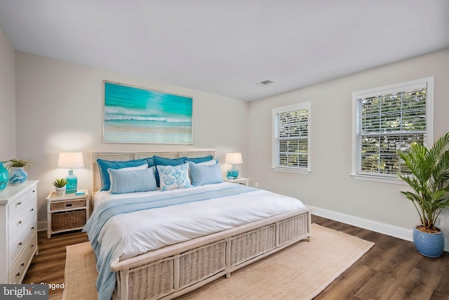 bedroom with wood finished floors, visible vents, and baseboards