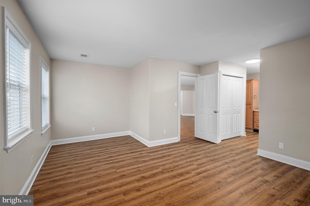 unfurnished room featuring visible vents, baseboards, and wood finished floors