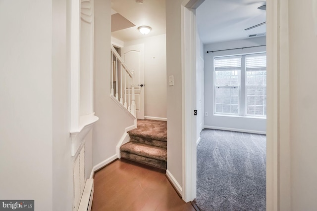 stairs with visible vents, baseboards, baseboard heating, and wood finished floors