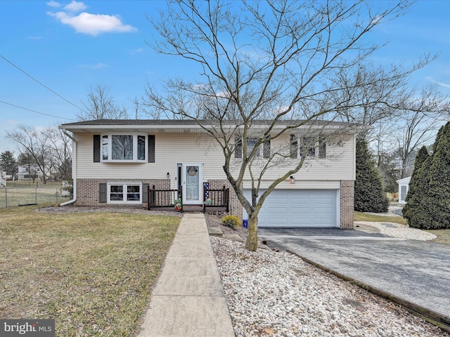 raised ranch with a garage, brick siding, a front lawn, and aphalt driveway