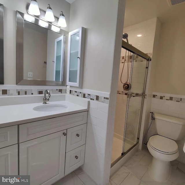 bathroom featuring tile walls, a stall shower, toilet, a wainscoted wall, and vanity