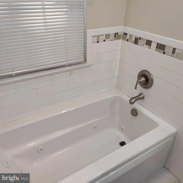 full bathroom featuring a tub with jets and tile walls
