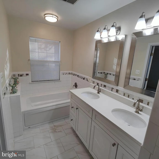 full bathroom with marble finish floors, a bath, and double vanity