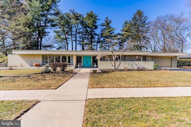 mid-century inspired home featuring concrete driveway, a front lawn, and an attached garage